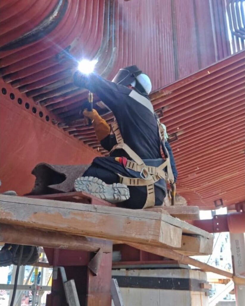 Рабочий варит в защитном костюме Рабочий варит в защитном костюме